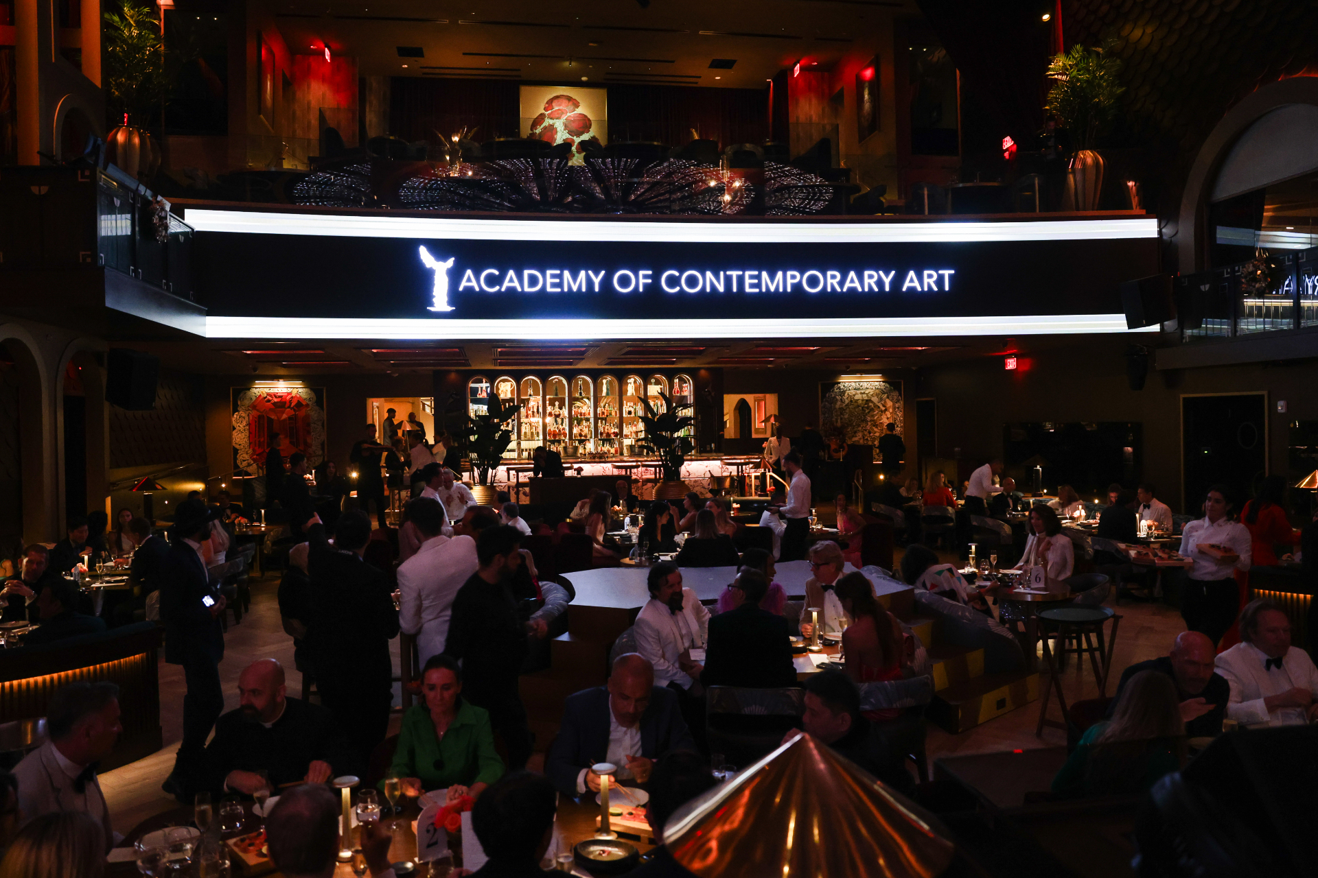 The Academy of Contemporary Art marquee sign glowing above a crowded gala dining room